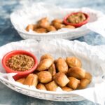pretzel bites in diner container with parchment paper and side of mustard in red dip cup