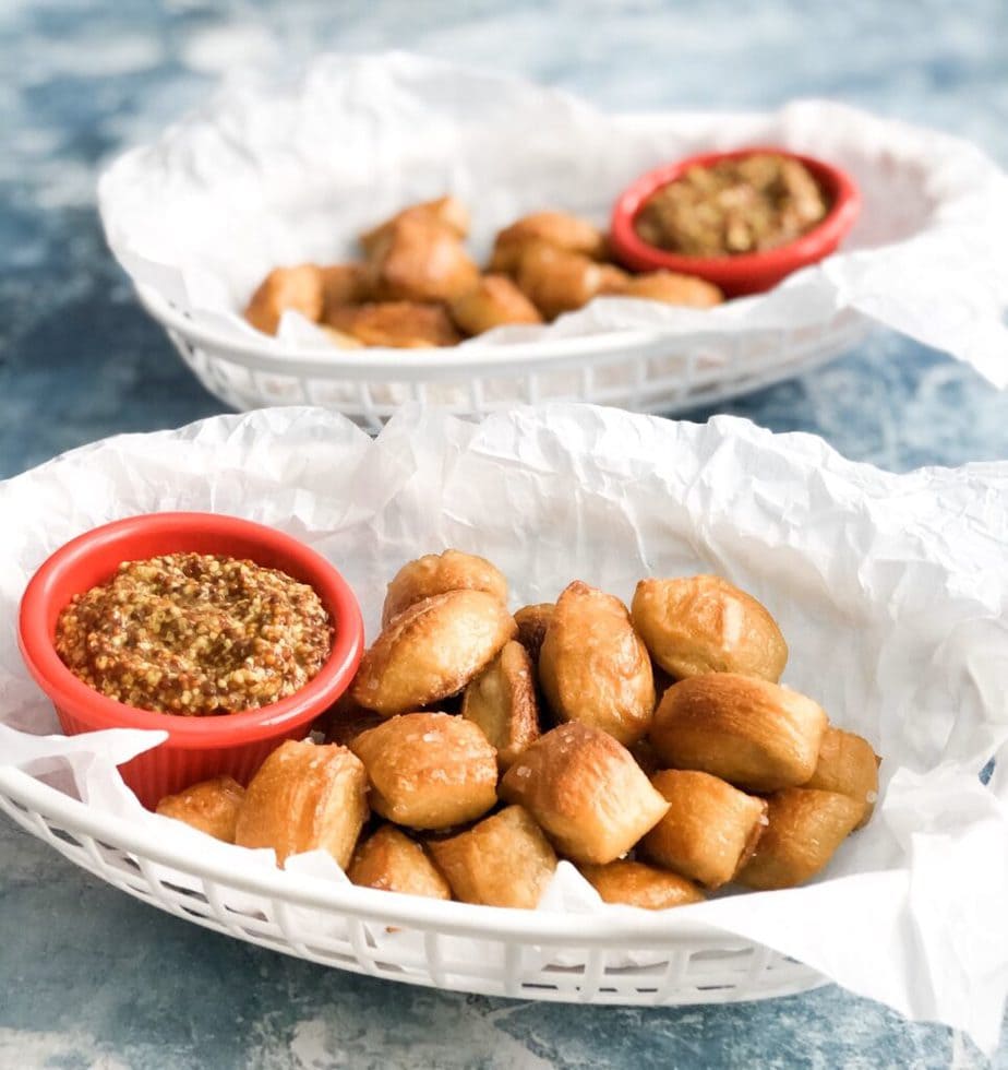 pretzel bites in diner container with parchment paper and side of mustard in red dip cup