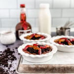 chocolate pudding in white round dishes topped with crushed Oreo cookies and gummy worms