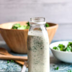 ranch dressing in a milk bottle with a bowl of salad in the background