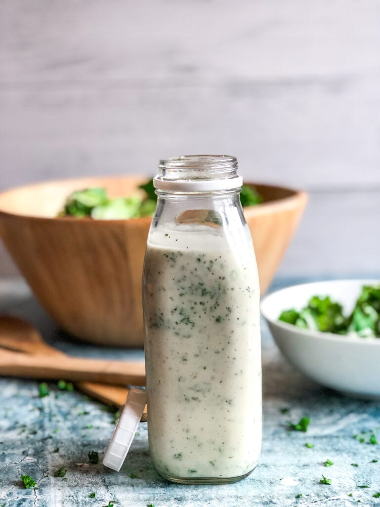 ranch dressing in a milk bottle with a bowl of salad in the background
