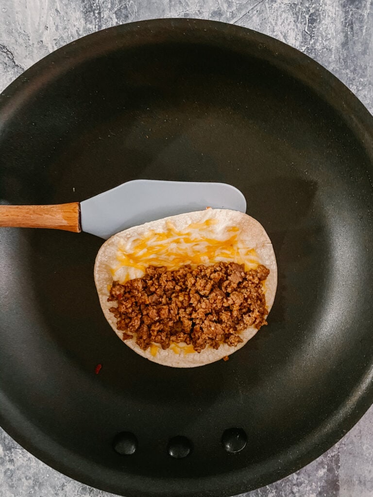tortilla with melted cheese and ground beef in large skillet