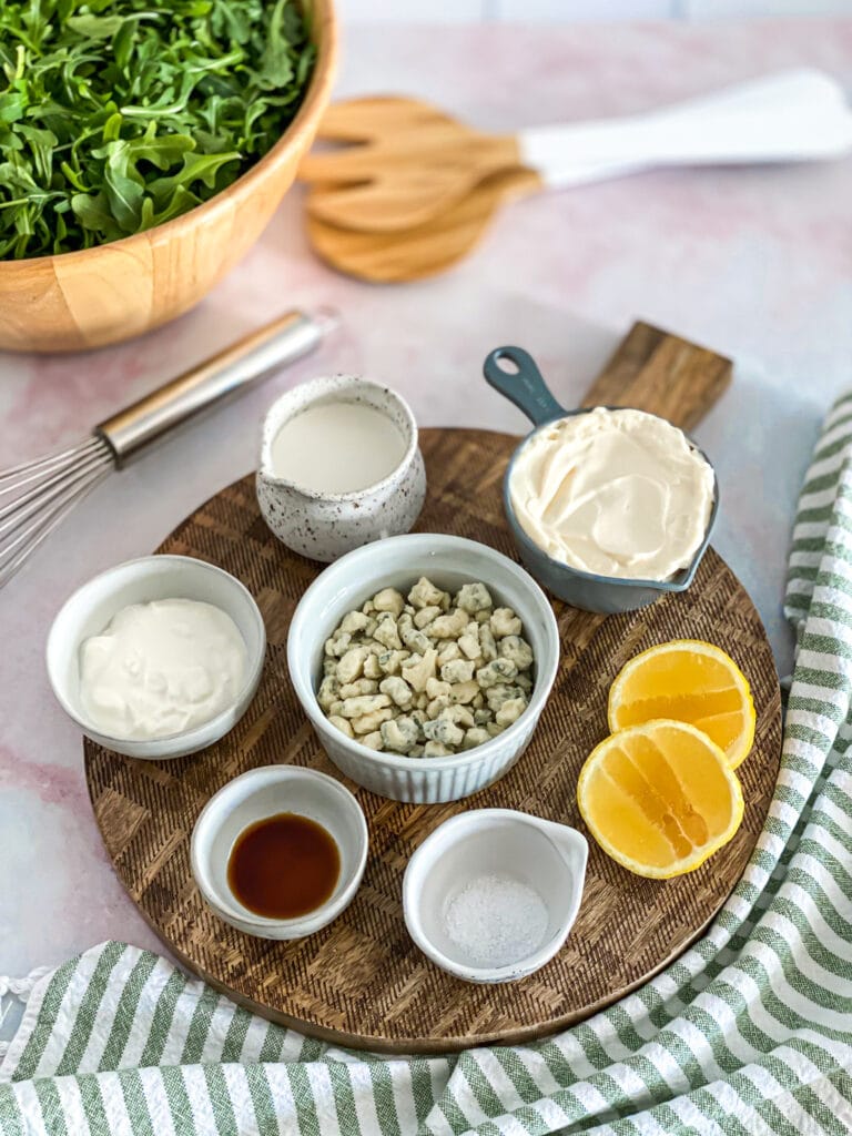 dressing ingredients portioned out into cups and laid out on a wooden serving board