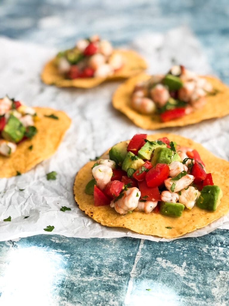 shrimp ceviche with tomatoes and avocado on top of round tostada shells