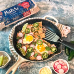 white skillet with chilaquiles and an egg carton off to the side