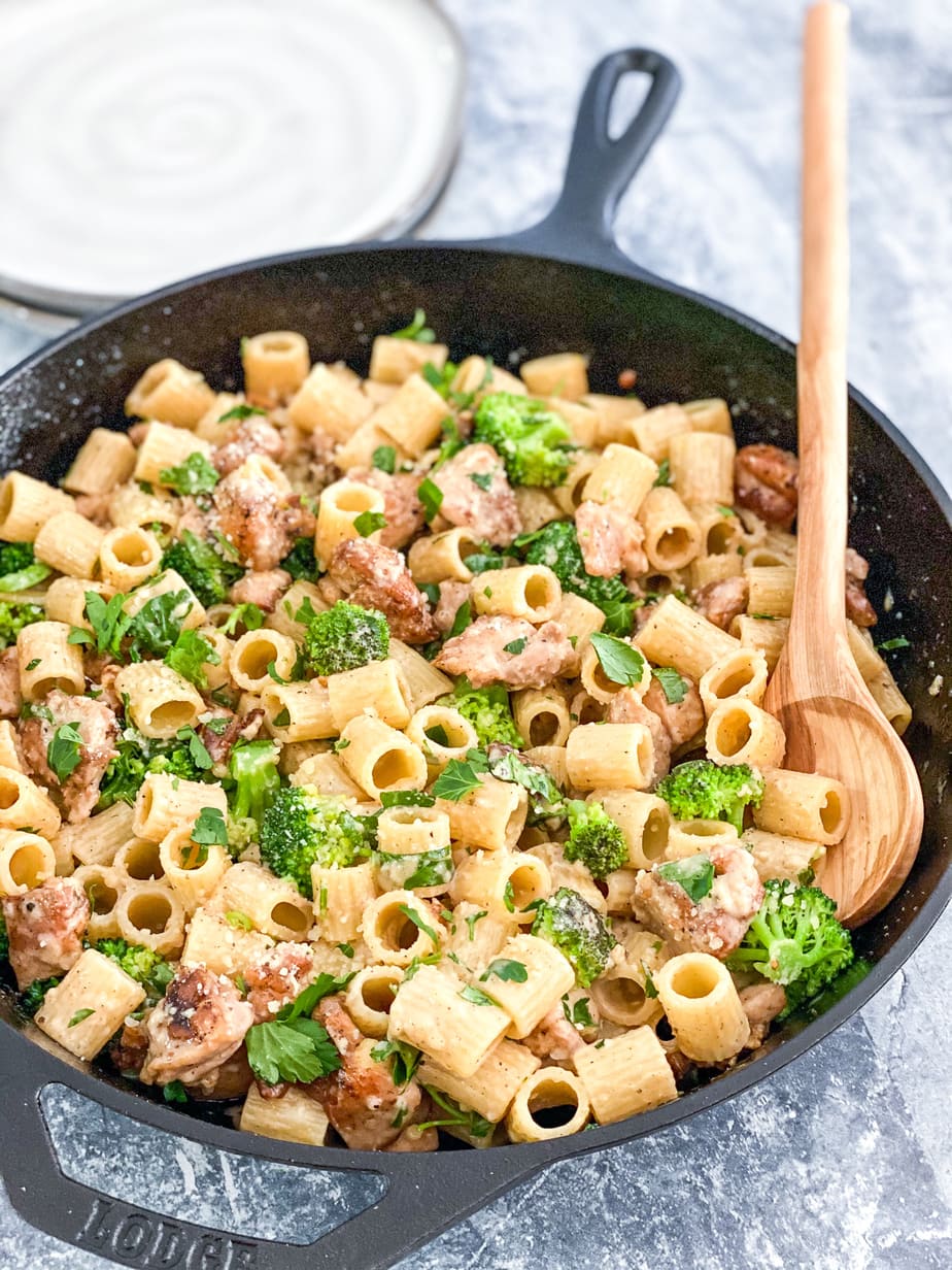 creamy chicken pasta in cast iron skillet with wooden spoon