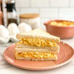 egg salad sandwich on white bread served on pink plate