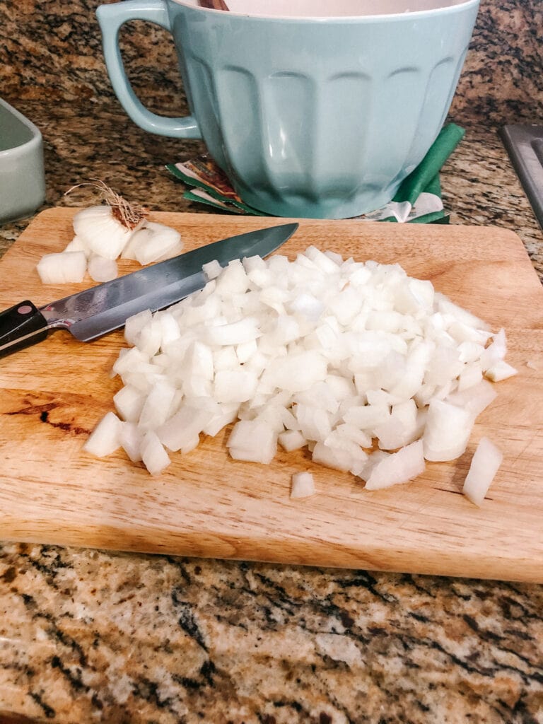 chopped onions on a cutting board with chefs knife next to them