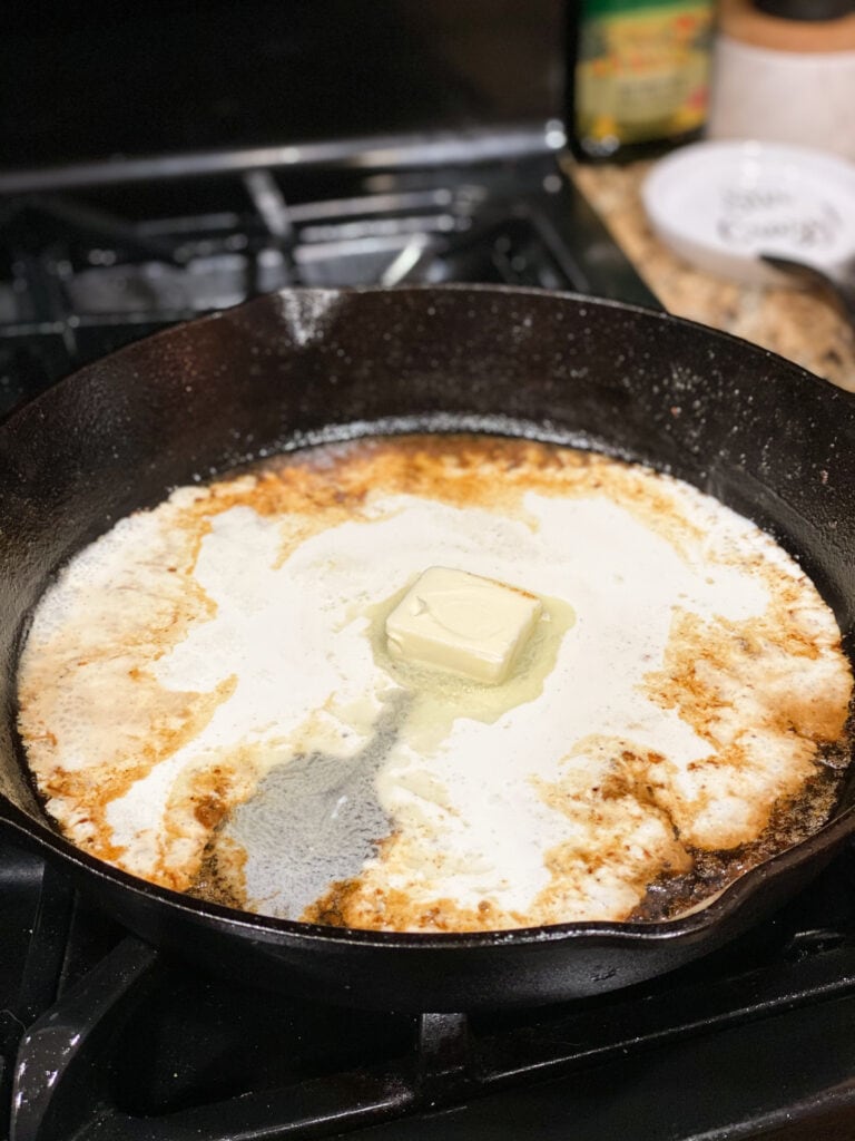 white wine simmering in cast iron skillet with butter and cream added