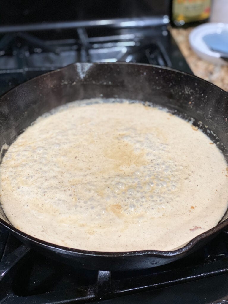 white wine simmering in cast iron skillet with butter and cream added and bubbling