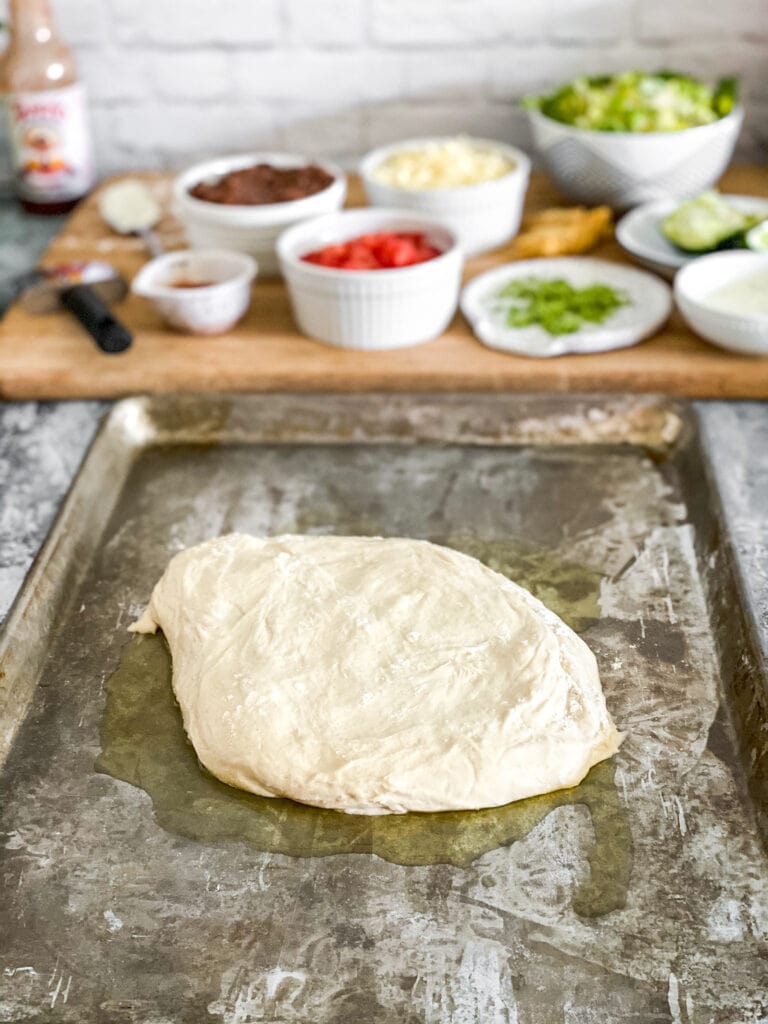 raw pizza dough for vegetarian taco pizza, on a sheet pan with olive oil