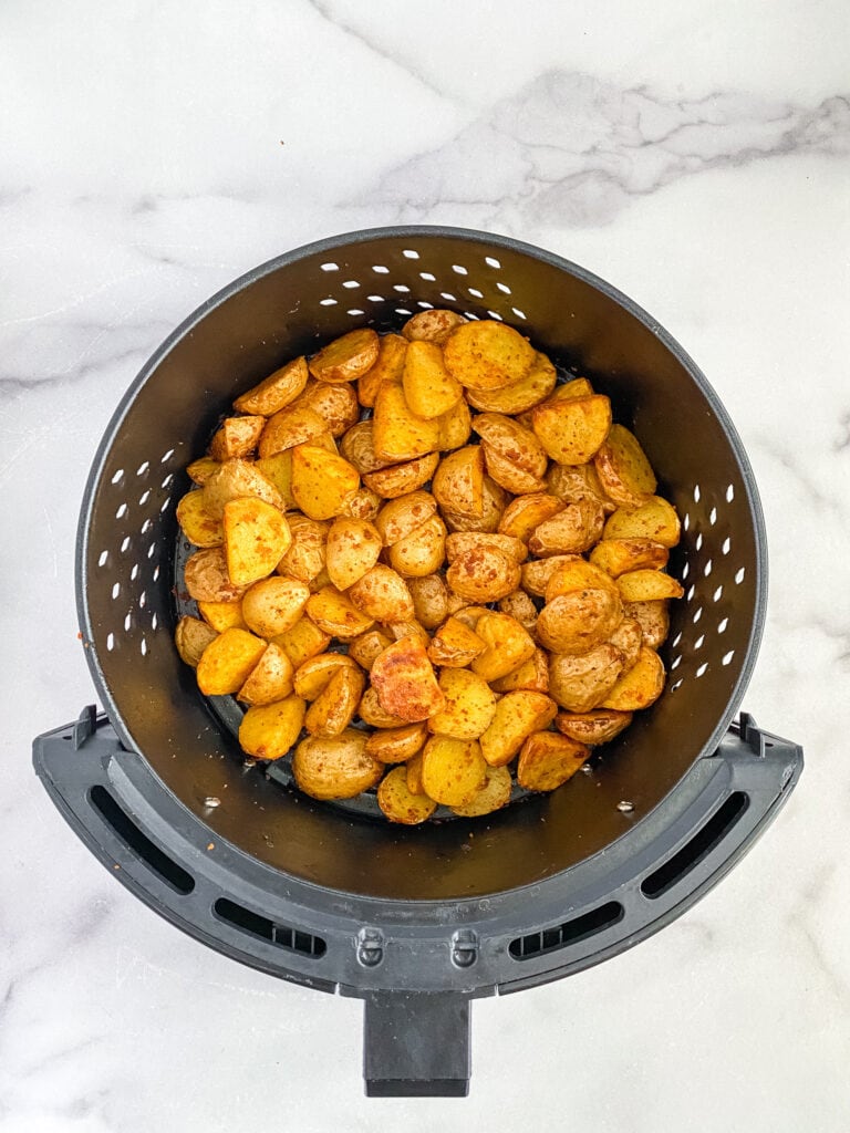 seasoned potatoes sitting in the air fryer basket after being cooked