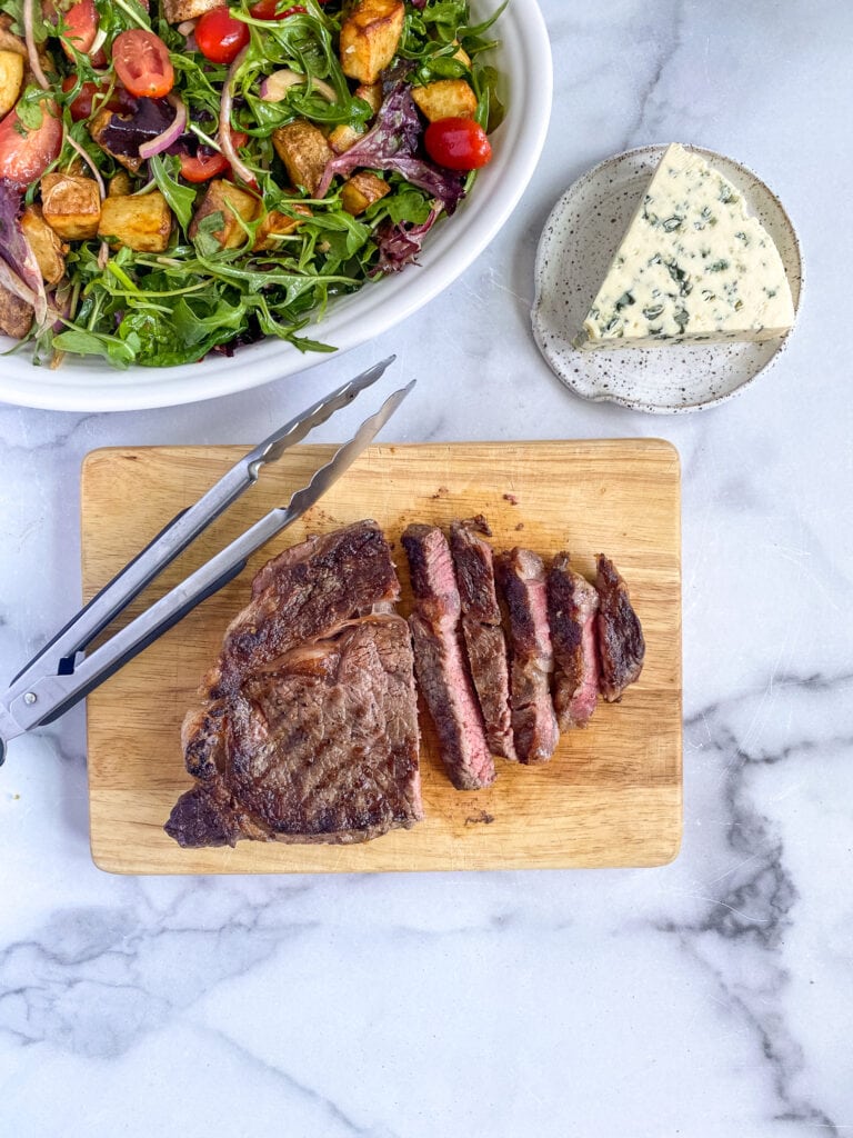 ribeye steak perfectly seared on a cutting board, sliced
