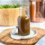 creamy balsamic dijon dressing in small glass jar for serving with bowl of salad in the background