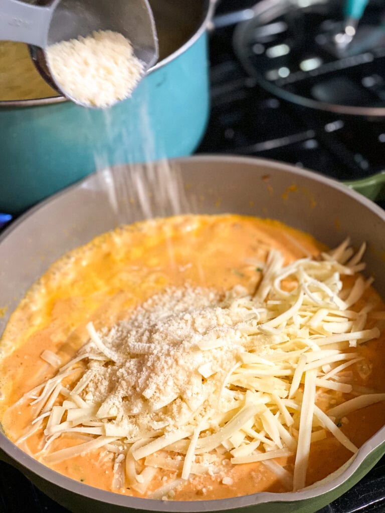 Pumpkin sauce in the pan with gruyere and parmesan cheese on top before being mixed in.