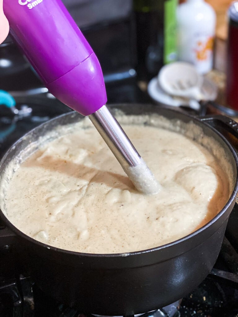 Potato soup being blended with an immersion blender right in the pot.