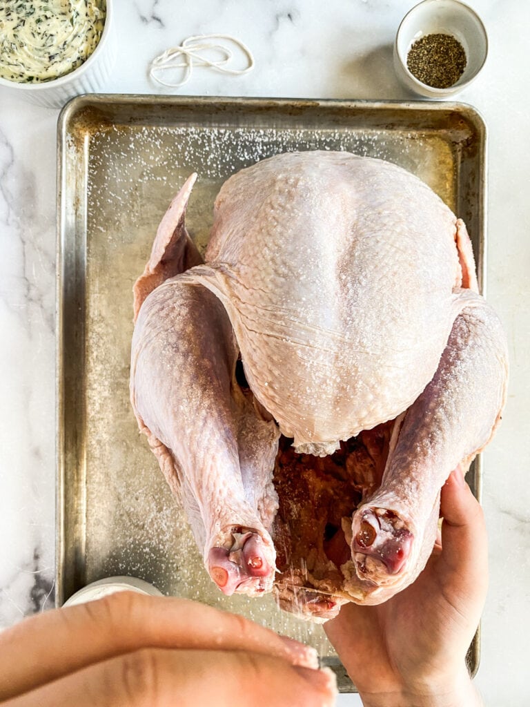 raw turkey being sprinkled with salt, inside and out.