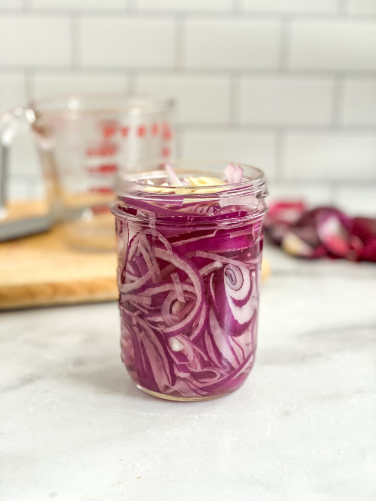 pickled red onions before being pickled, in a mason jar.